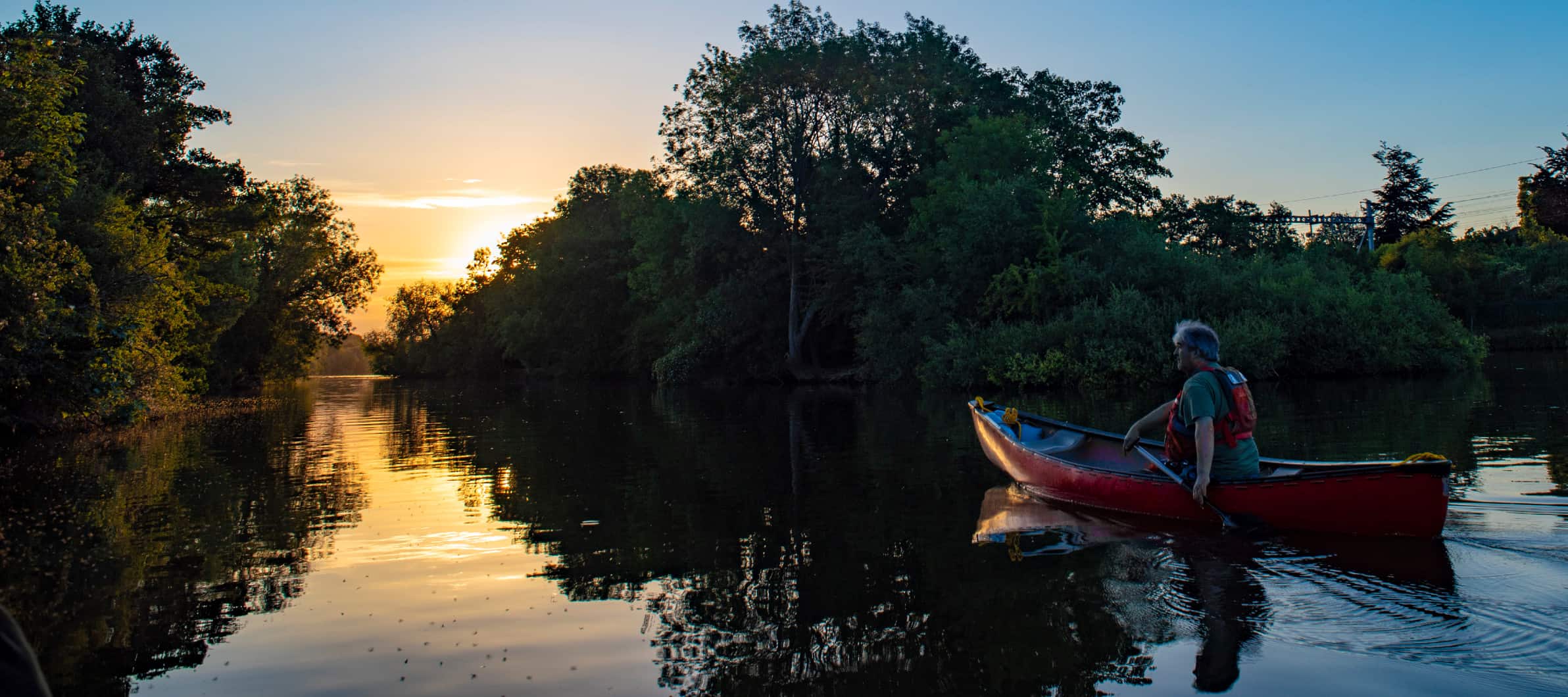 Canoe Foundation News and Projects. Image of paddler at sunset on river